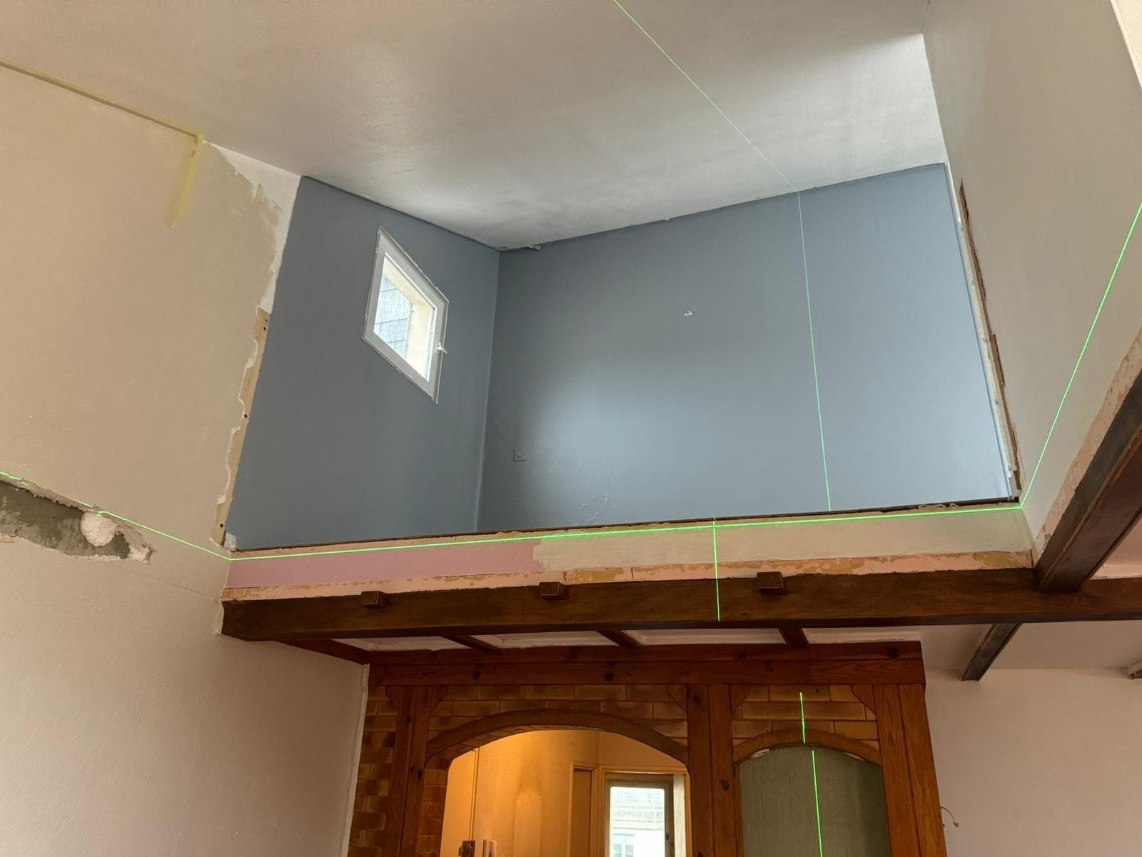 Mezzanine ouverte avant travaux, avec les tracés laser de la future cloison en placo